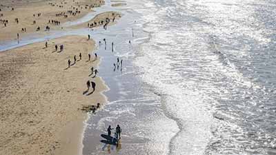 Badgasten aan de vloedlijn van een breed Noordzeestrand in Zeeland