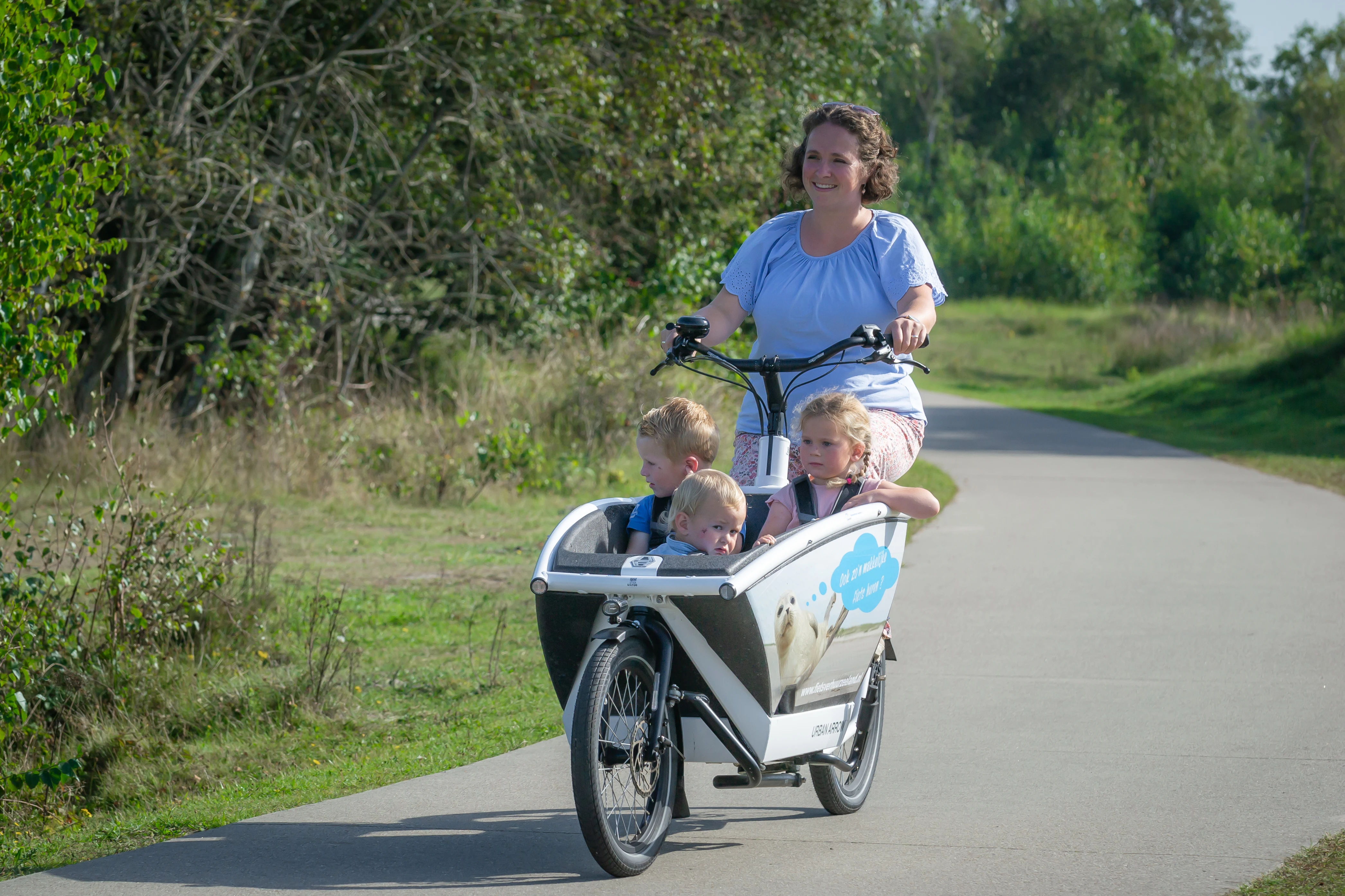 Moeder op de fiets met 3 kinderen langs de kust
